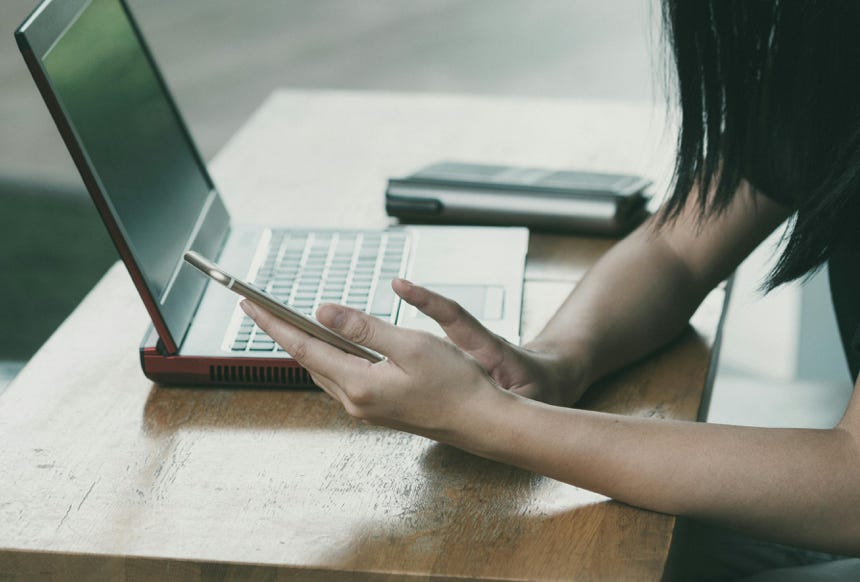 Woman Sitting on Chair Beside Table While Using Phone